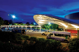 The curved triangular truss of the Wyong Rugby League Club porte cochère is held in place by two very large stainless steel pins at each end.  In a neat trick of efficiency, the universal beam also acts as a rain gutter. Photo: Shade To Order Pty. Ltd.