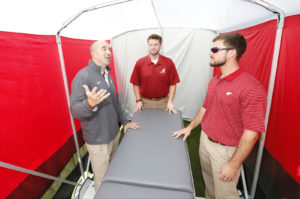 Jeff Allen (left) and two  University of Alabama mechanical engineering students discuss the medical privacy tent developed for Crimson  Tide football. Photo: Robert Sutton, University of Alabama.