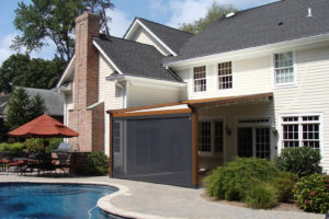 The wooden Gennius, resembling a pergola, provides this private residence with a comfortable outdoor entertaining area, using a retractable awning that provides protection from both UV rays and inclement weather on the south-facing patio. The view of the pool remains unobstructed. Window Works of Livingston, N.J., did the installation. Photo: KE Durasol Awnings Inc.