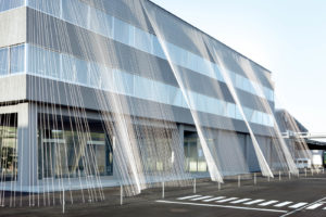 Textile manufacturer Komatsu Seiren applied its own fiber-reinforcing products to its former office building to stabilize the structure against future earthquakes, linking roof to ground via cables made of carbon fiber composite. Photo: Takumi Ota.