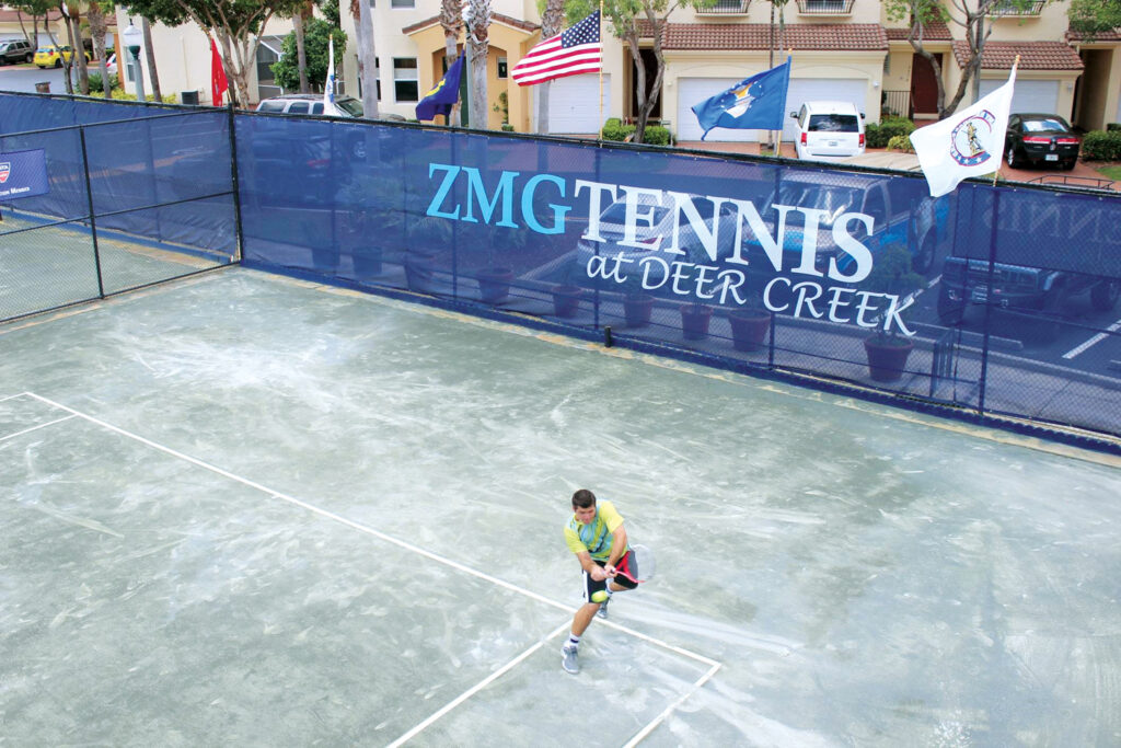 Outdoor fabrics create a windscreen around a tennis court.