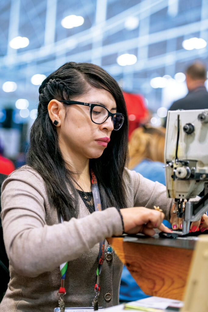 The demo area at Advanced Textiles Expo shows hands-on techniques, such as sewing bags in 2022.
