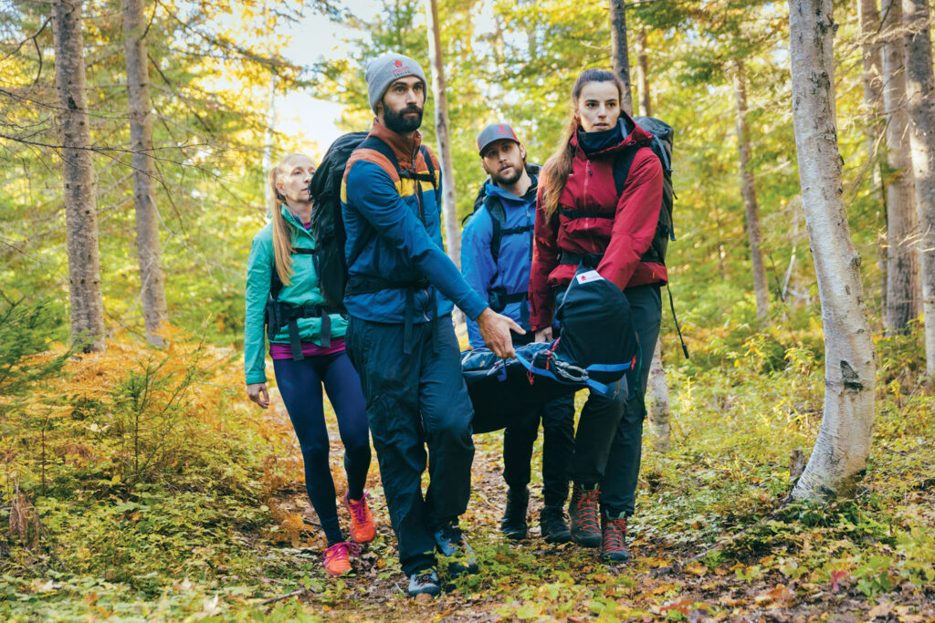 Four people carrying someone out of the woods using the nanoTRAINO stretcher.