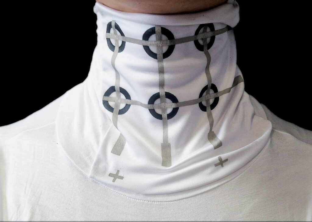 Close-up of the neck of a smart textile pajama top that integrates sensors to detect sleep disorders. The sensors include six black circular rings with intersecting silver lines through them.