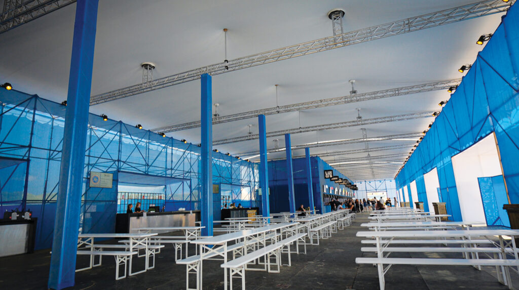The inside of an indoor market and cafeteria with blue walls and white benches.