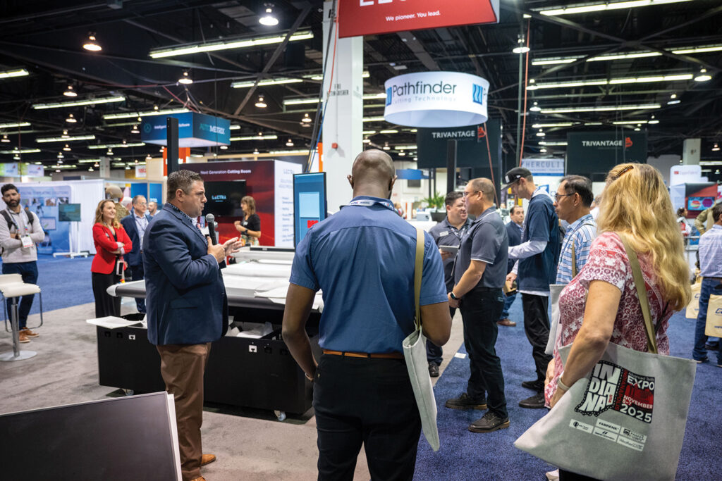 Equipment manufacturers demonstrate their equipment on the show floor. Here people are gathered in the Pathfinder booth to look at cutting equipment.