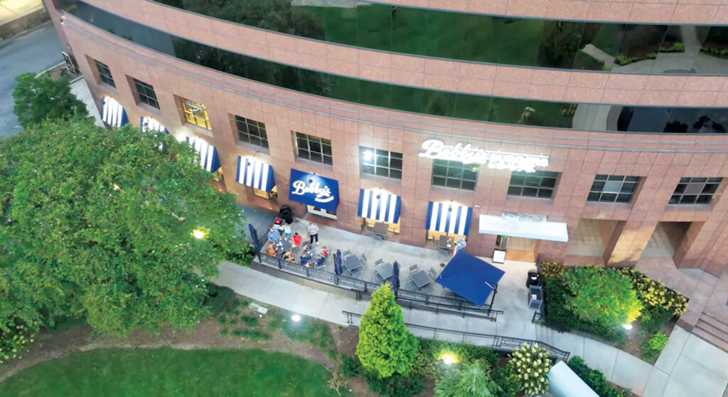 A drone shot of obby’s Burgers by Bobby Flay, in Charlotte, N.C. showing the blue-and-white striped awnings on the front of the restaurant