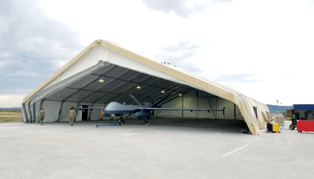 A Large Area Maintenance Shelter as seen from the outside, with a drone airplane inside