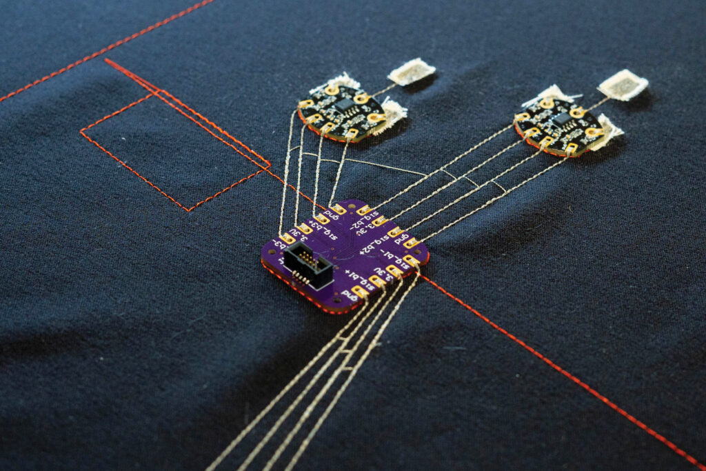 A close-up of a fabric calf sleeve that shows red and yellow embroidered circuitry.