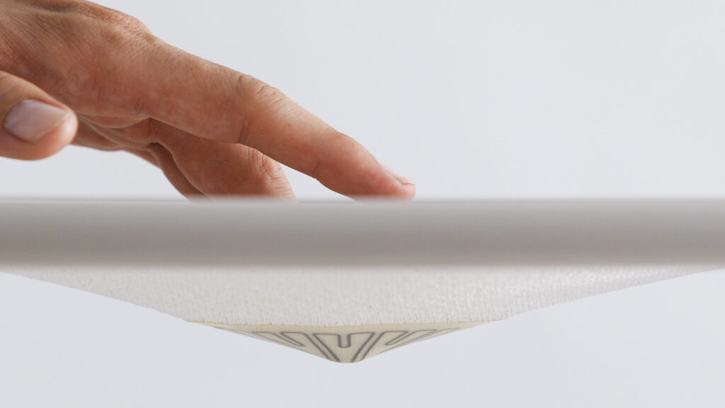Close-up of a finger pushing down on the center section of the textile to turn the lamp on.