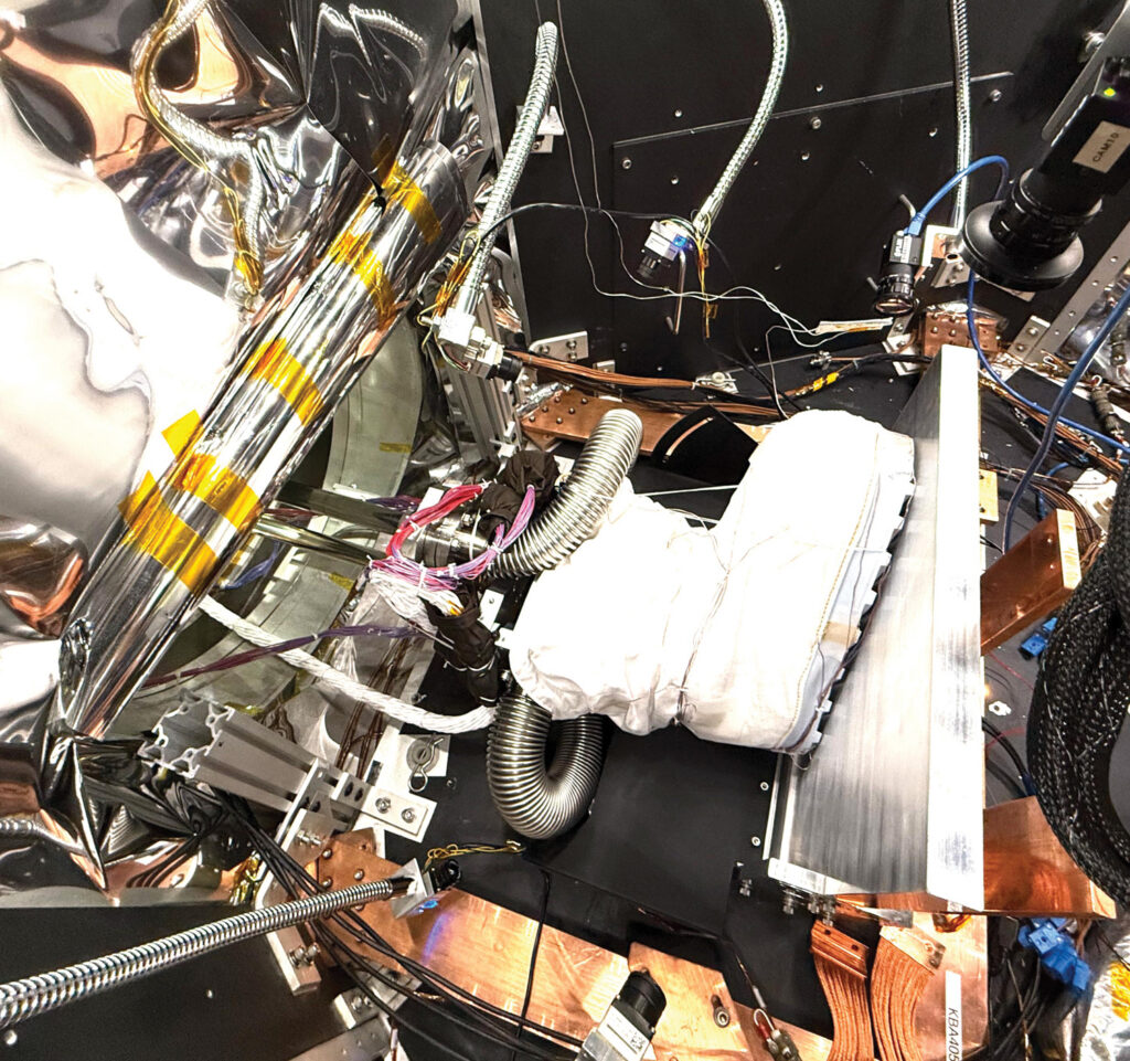 Close-up of a lunar boot test setup, featuring a white boot, metallic surfaces, and various wires and sensors in a complex arrangement.
