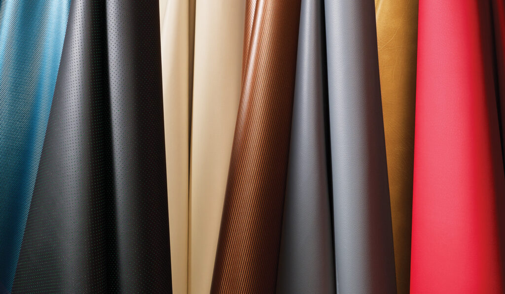 A collection of upholstery fabrics in shades of blue, black, beige, brown, gray, gold and red, arranged in folds.