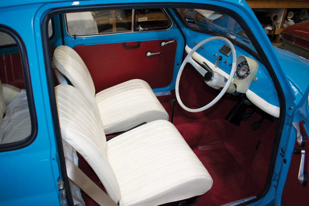 Bright blue car featuring white striped seats and deep red accents, with a "classic" steering wheel and dashboard.