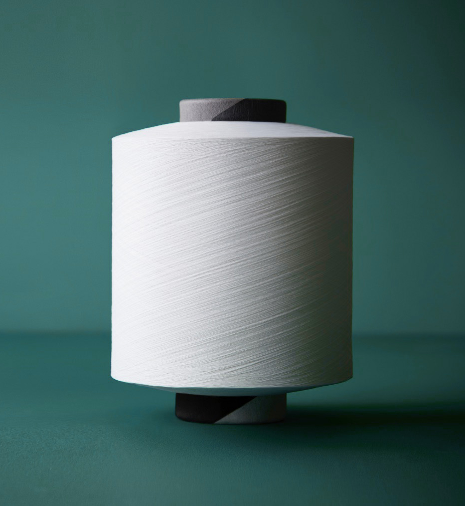 CiClo image option 1 White spool of yarn stands upright against a teal background, featuring a dark grey top and a black and grey base.