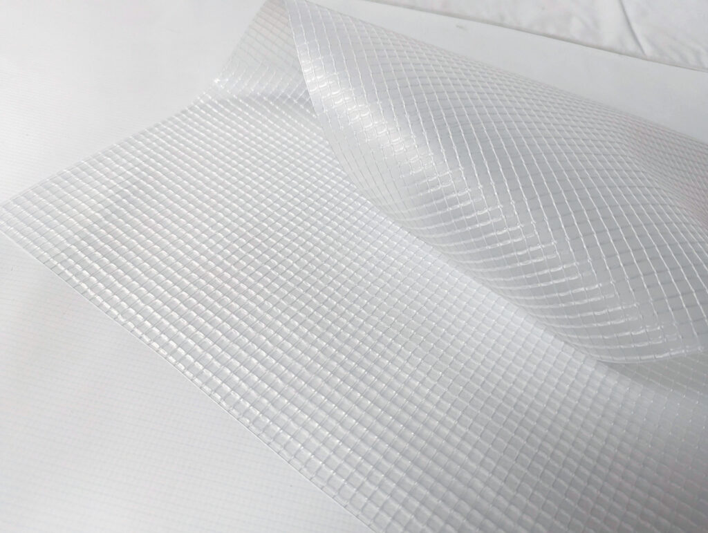 Translucent agricultural fabric featuring a textured grid pattern, partially unrolled on a smooth white surface.