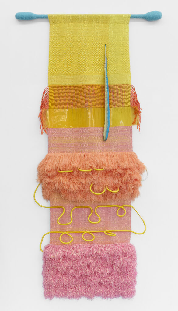 Colorful textile artwork featuring layered patterns in yellow, orange, and pink, with textured elements and playful yellow lines.