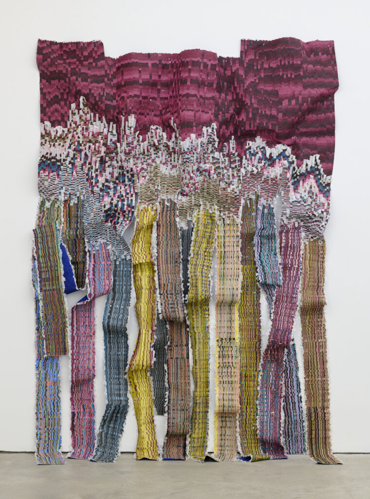 Wavy textile art features a gradient of pink and maroon at the top, transitioning to colorful strips of fabric in various hues below.