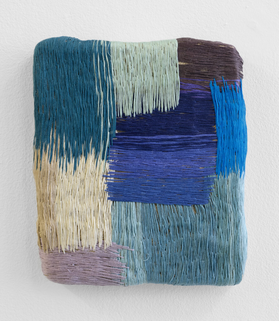 Textured artwork featuring vibrant threads in shades of teal, blue, purple, and beige, arranged in a patchwork design on a white background.