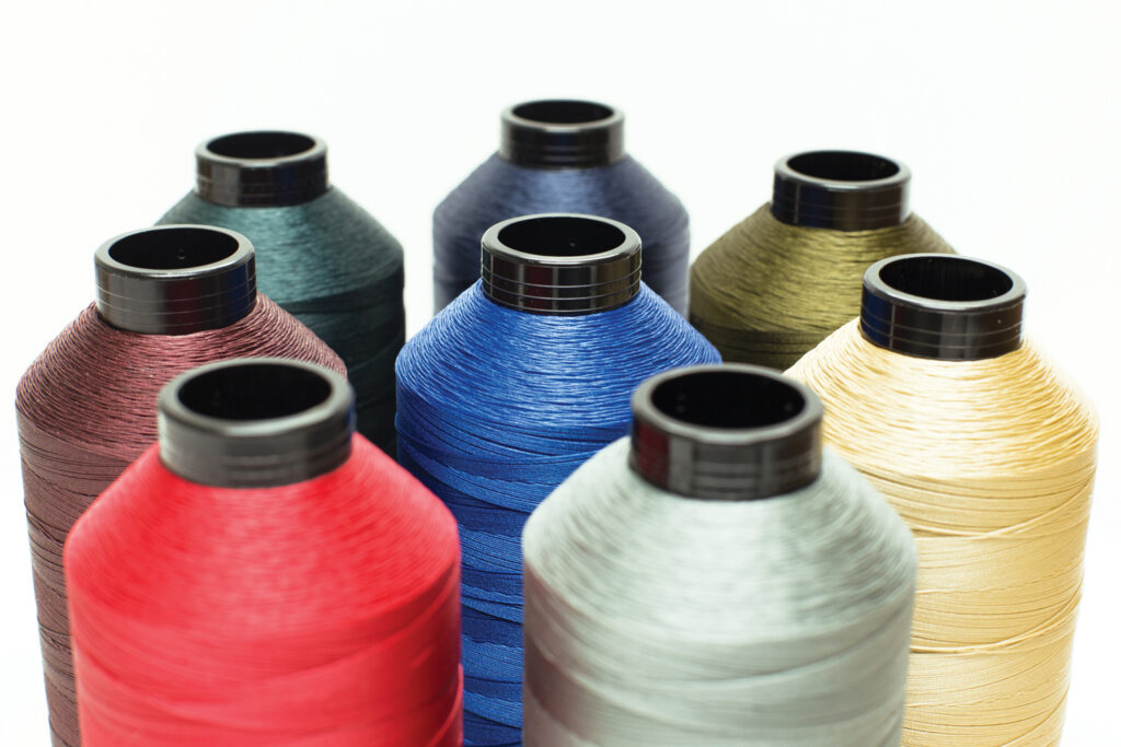 Spools of colorful Fil-Tec thread in various shades arranged in a circular layout, showcasing hues of red, blue, green, light yellow and gray.