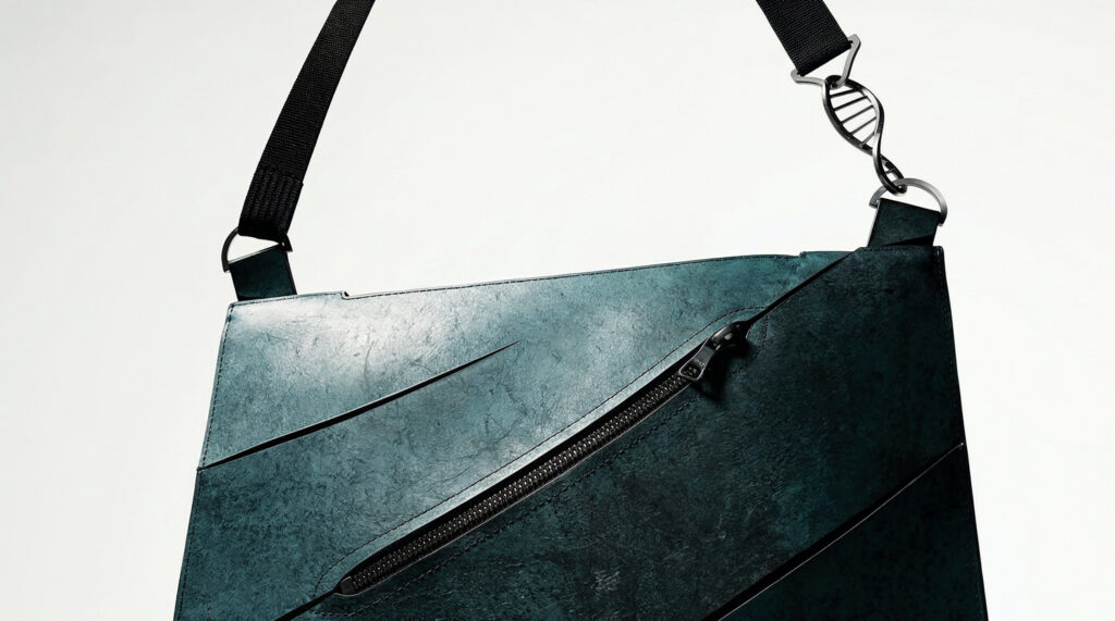A sleek, dark turquoise bag with a textured finish, featuring angular lines and a zipper, suspended by a black strap.