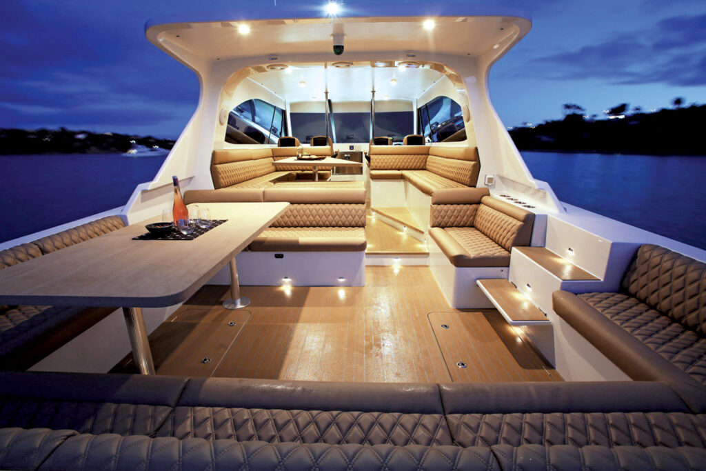 Luxurious yacht interior with plush seating, wooden table and soft lighting, set against a twilight sky.