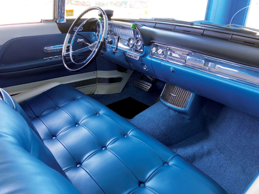 Bright blue tufted leather interior of a classic Cadillac Eldorado Brougham, featuring a polished dashboard, chrome accents, and plush blue carpeting.