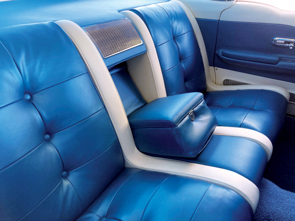 Luxurious blue leather upholstery with white trim in the back seat of a restored Cadillac Eldorado Brougham. The upholstery features tufted detailing and a central armrest as well as matching white and blue on the interior of the doors.