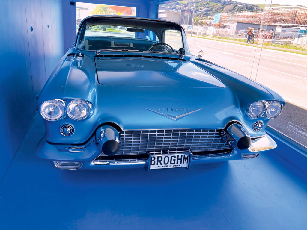 The sleek front of a restored Cadillac Eldorado Brougham in vibrant blue, with chrome accents and a unique license plate.