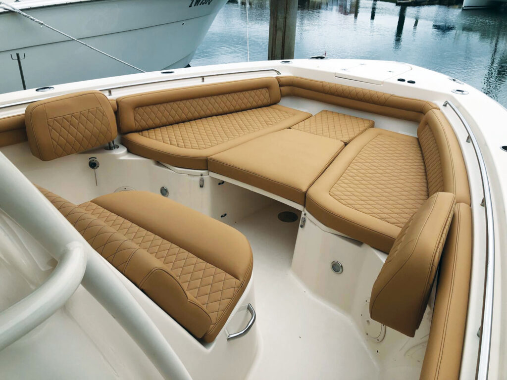 Tan leather seating arranged in a boat, featuring diamond-patterned stitching, with water and other boats in the background.