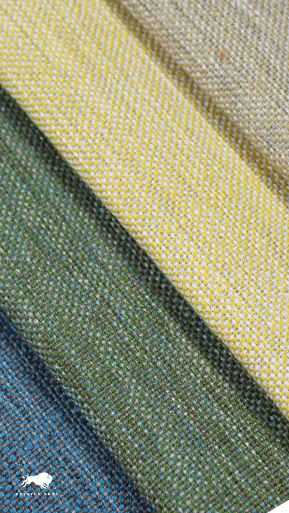 Four layers of textured fabric in varying colors: yellow, green, blue, and beige, arranged with visible threading patterns.
