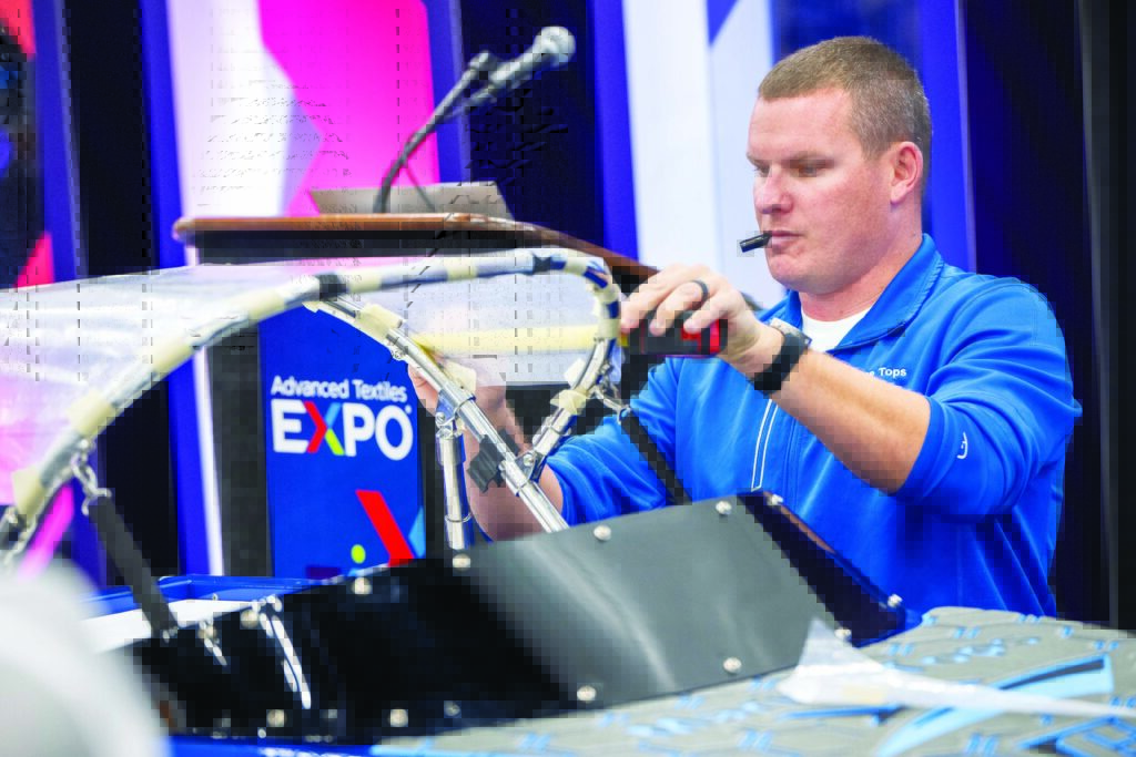 Kyle Van Damme, MFC, of Marine Tops Unlimited Inc., in a blue shirt, demonstrated traditional patterning with a small boat model as a part of the Marine Fabricators Roadshow sessions at Advanced Textiles Expo.