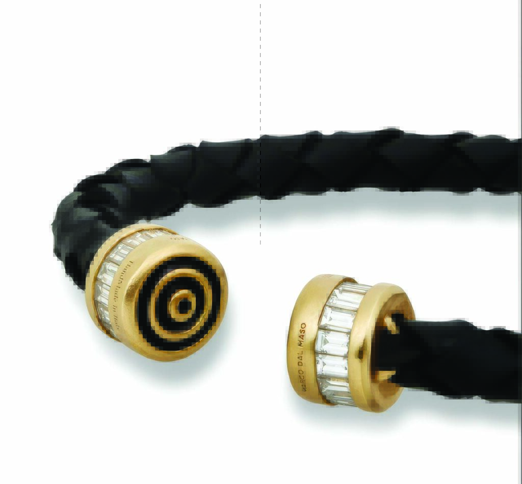 A braided black fabric bracelet with golden endcaps featuring circular and rectangular embellishments.