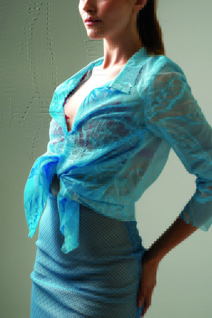A model wears a light blue 3D-printed mesh fabric top tied at the waist, paired with a patterned blue skirt, set against a neutral background.