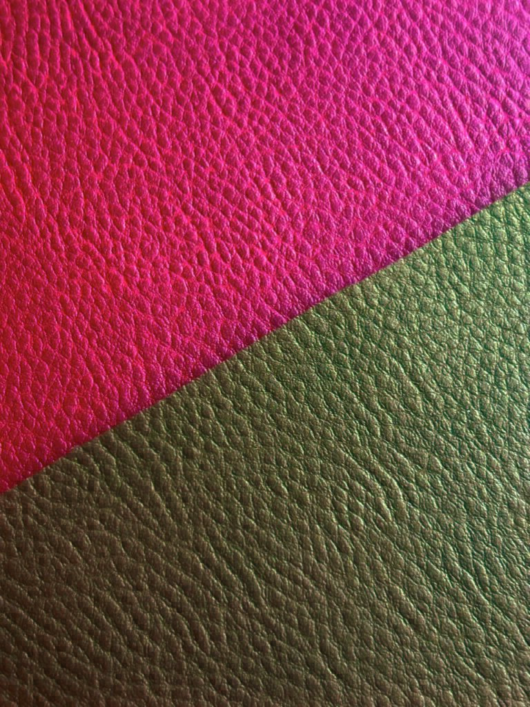 Close-up of textured material divided diagonally; vibrant pink on the top half and deep green on the bottom half.