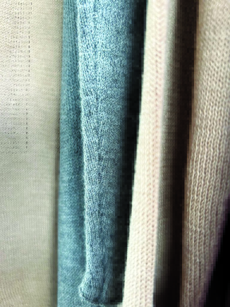 Close-up of three folded fabric swatches in soft hues: beige, light teal, and pale pink, showcasing texture and color variation.