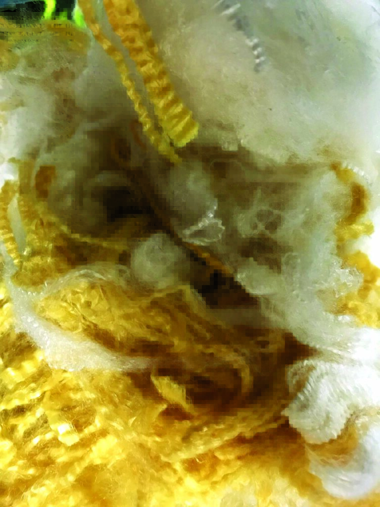 A close-up of mixed yellow and white Nomex® and Kevlar® aramid staple fibers, showcasing their textured, fluffy appearance intermixed with twisted strands.
