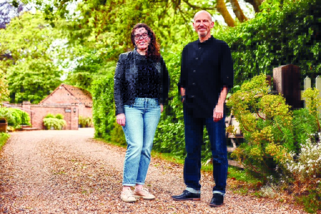 Two leaders from Global Change Award winner Rhea's Factory, Arzu Sandıkçı, founder and CEO, and Mert Topcu, chief technical officer, stand on a gravel path lined with greenery, wearing casual attire, smiling against a backdrop of trees and rustic buildings.