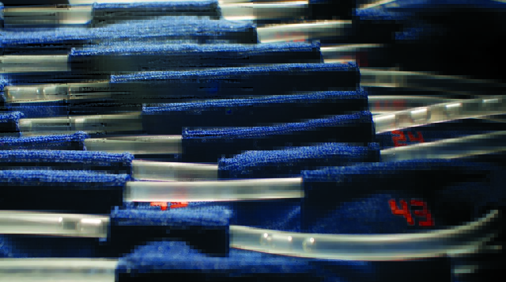 Close-up of a series of clear plastic tubes running through blue fabric channels in the Axiom and Prada LCVG suit. The photo also shows red numbers on the fabric.