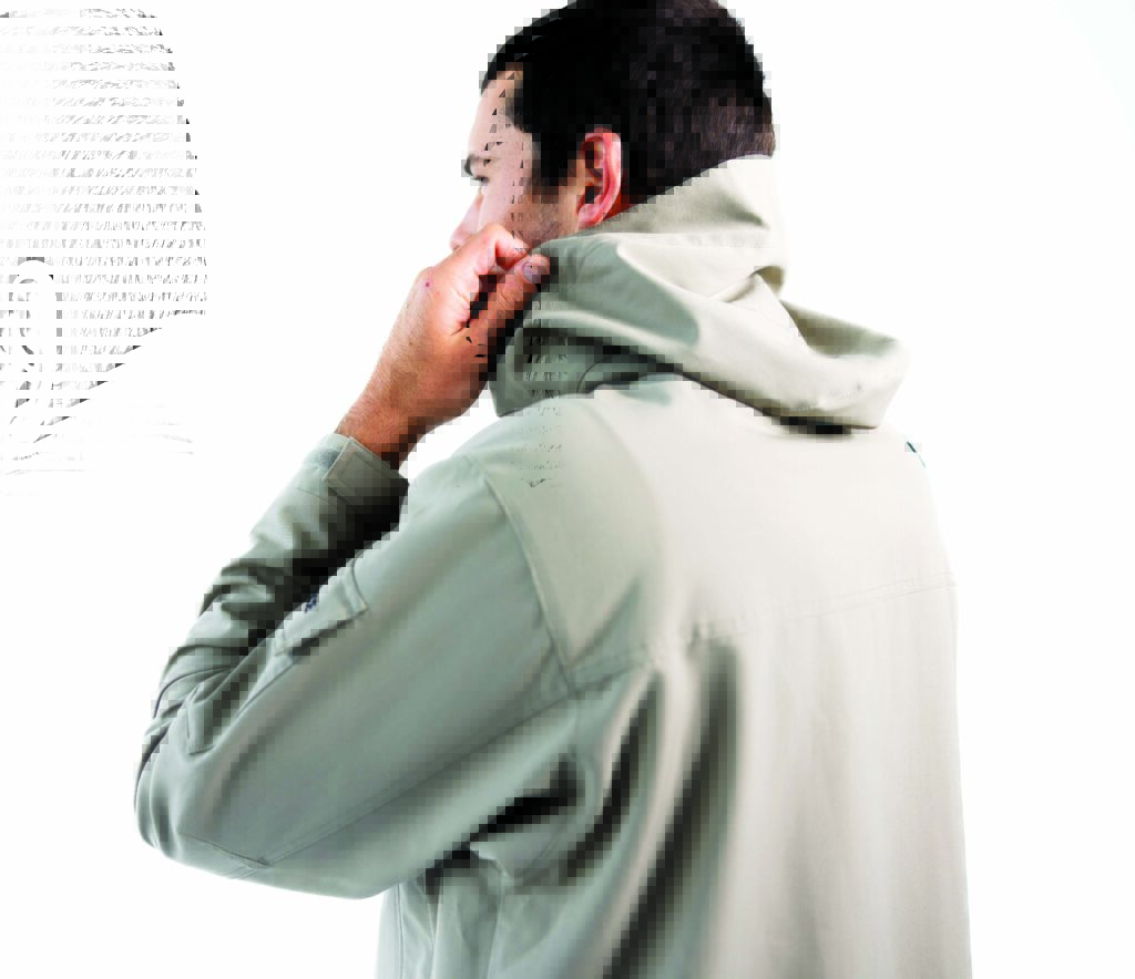 Man in a light grey hoodie, showcasing a cozy collar, with his hand adjusting the neckline, set against a white background.