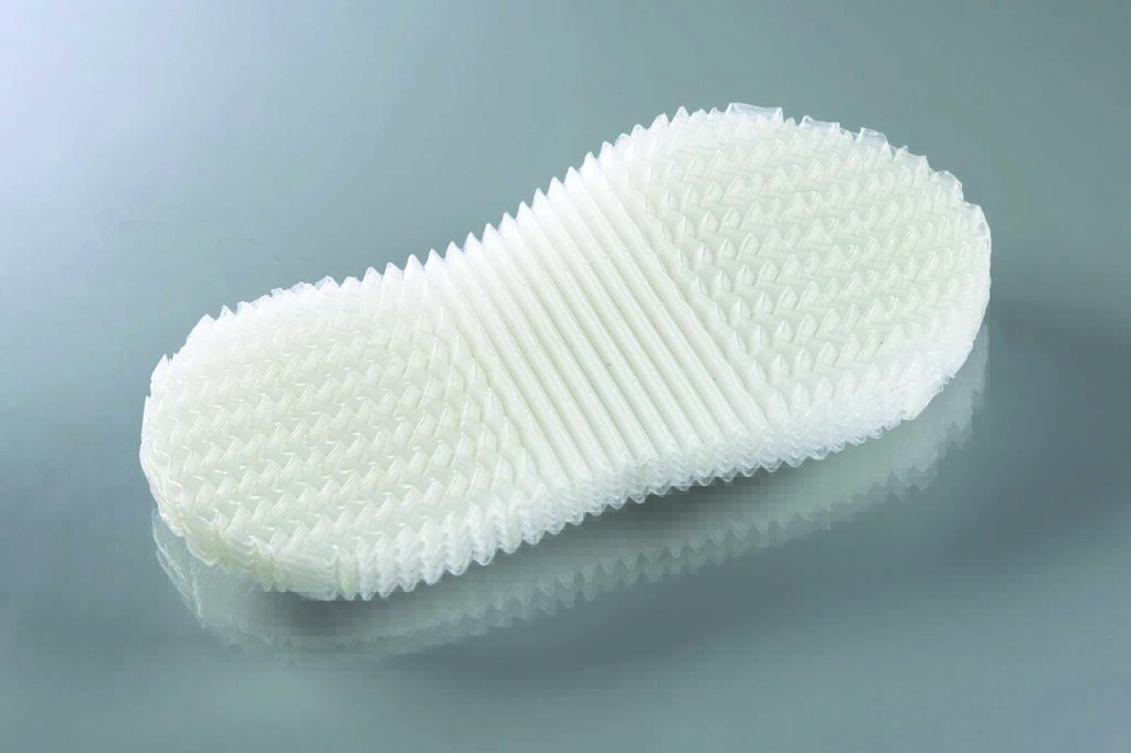 Textured white shoe sole displayed on a reflective surface, showcasing a unique design with ridges and a futuristic appearance.