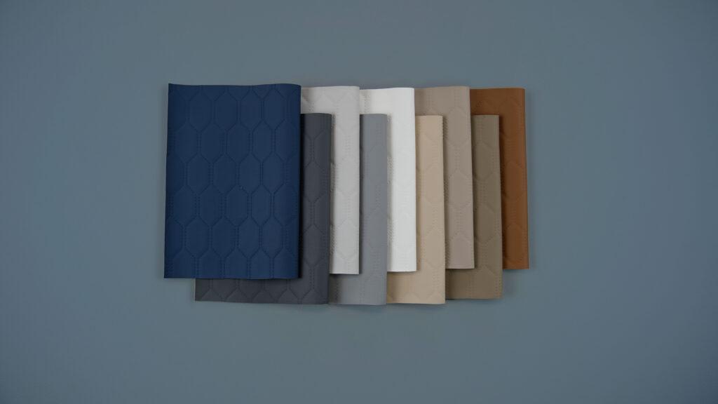 Stack of eight varying-colored textured materials arranged in a gradient, featuring shades of blue, grey, white, tan, and brown on a grey background.